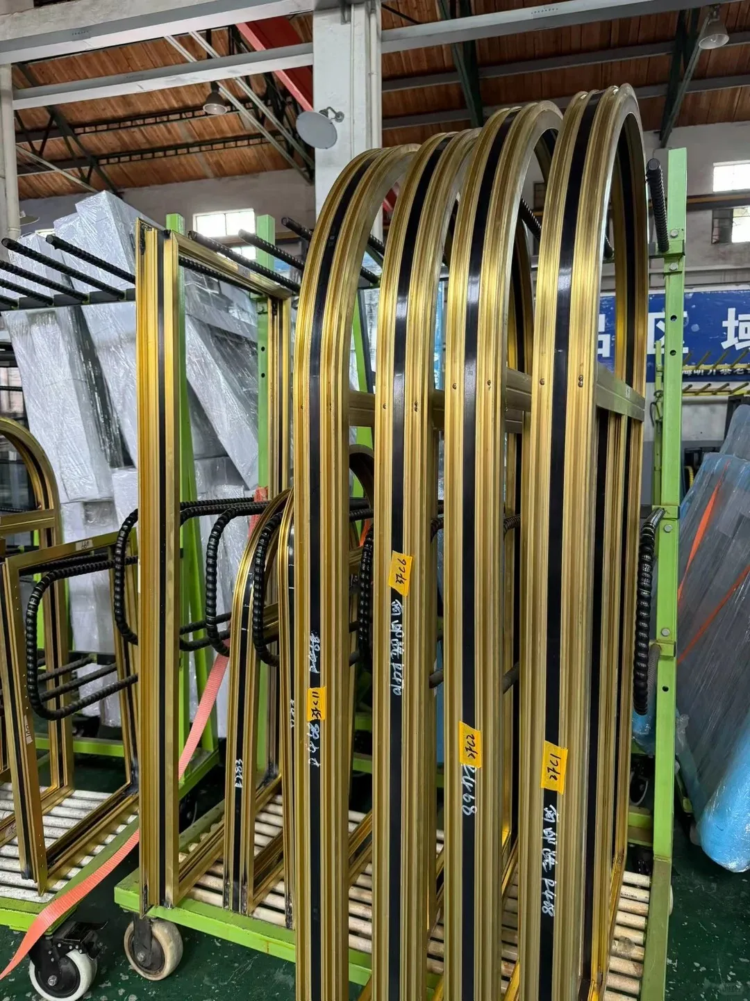 Brass profiles bent to a specific radius and racked in the workshop, ready for glazing and assembly. Precision forming is what allows arched and curved brass windows to be made to a sketch rather than a catalogue number.